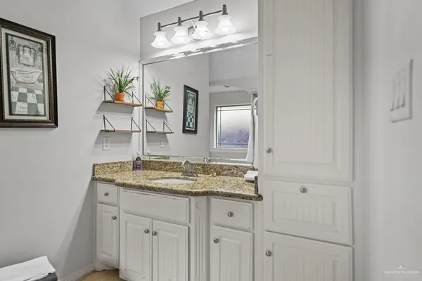 a bathroom with a granite countertop sink vanity and mirror