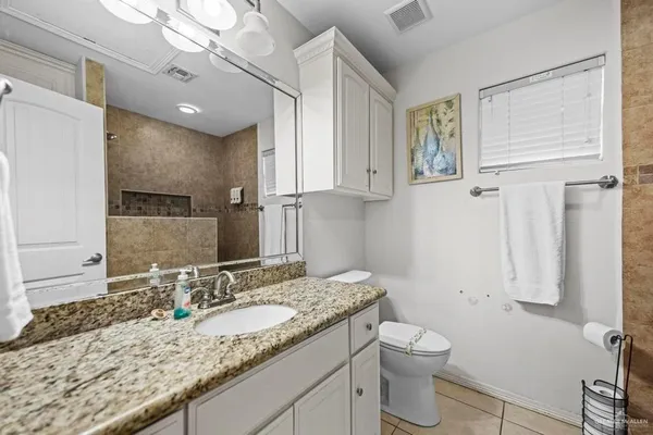 a bathroom with a granite countertop sink a toilet and a mirror