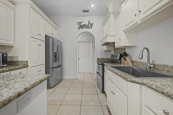 a kitchen with stainless steel appliances granite countertop a sink refrigerator and cabinets