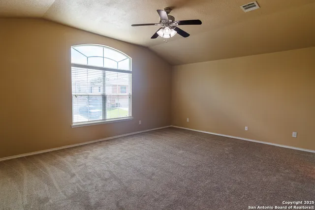 an empty room with windows and ceiling fan view