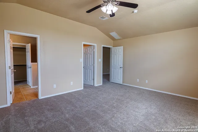 a view of an empty room with chandelier fan