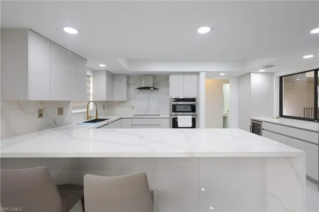 a large white kitchen with kitchen island a sink stainless steel appliances and cabinets