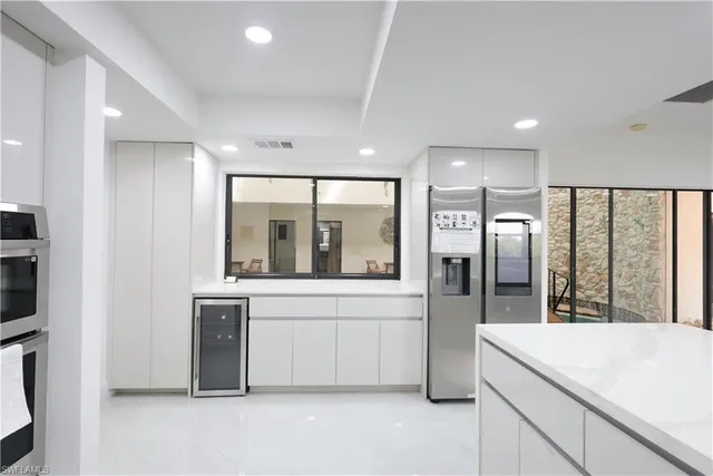 a large white kitchen with a large window and stainless steel appliances