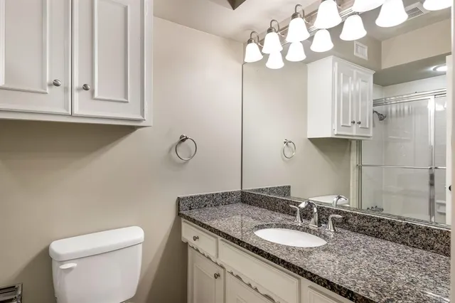 a bathroom with a granite countertop sink a toilet and a mirror
