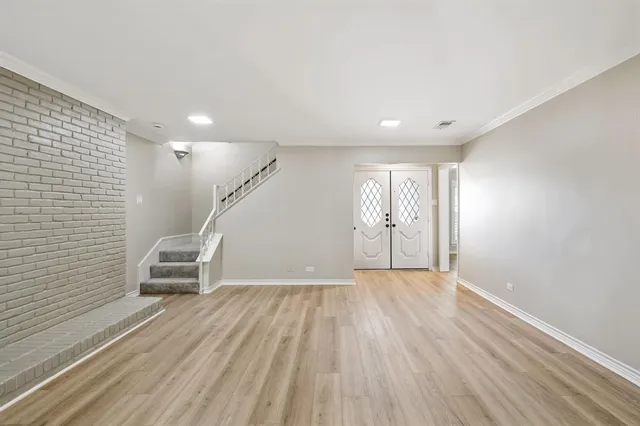a view of an empty room with wooden floor and stairs