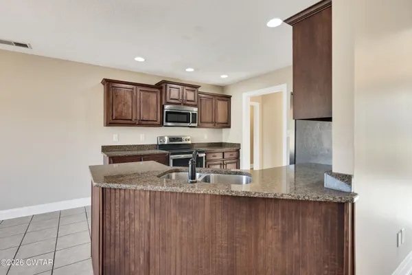 a kitchen with kitchen island granite countertop a stove sink and microwave