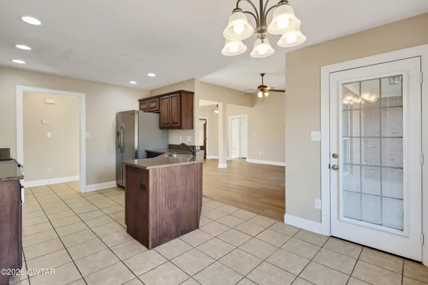 a kitchen with stainless steel appliances kitchen island granite countertop a refrigerator and a sink