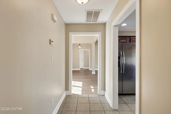 a view of a hallway with wooden floor and a bathroom