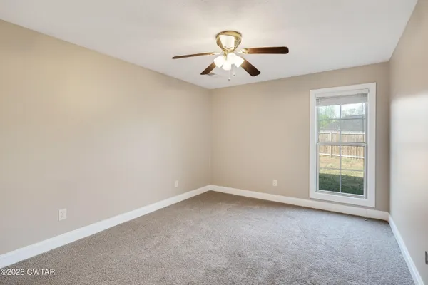 an empty room with windows and fan