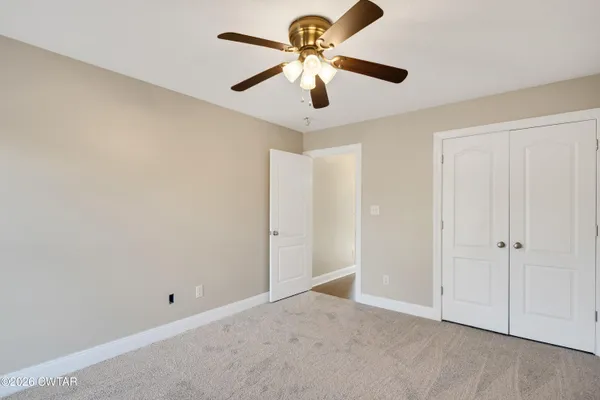 an empty room with closet and a chandelier fan