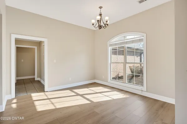 an empty room with wooden floor cabinet and windows