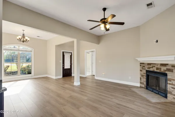 a view of an empty room with wooden floor fireplace and a window