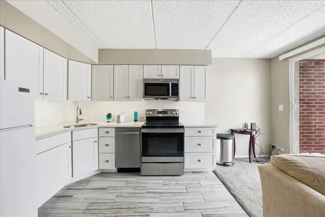 a kitchen with granite countertop a stove top oven a sink dishwasher and a refrigerator with wooden floor