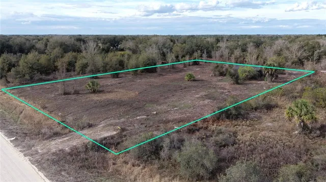 a view of a dry yard with wooden fence