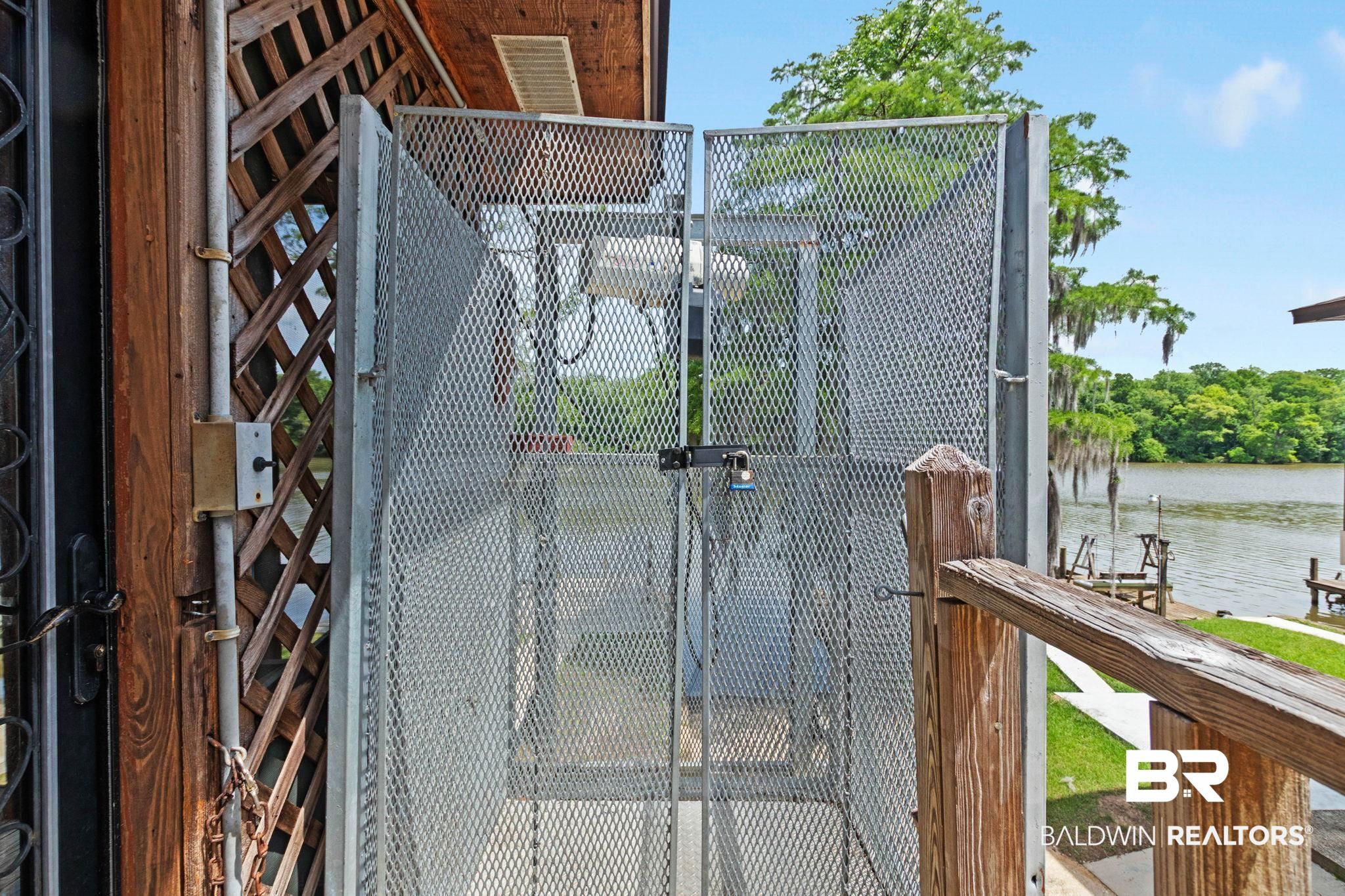 8153 Bryant's Lndg Road Stockton, AL 36579 - Photo 58 of 87 Outdoor cargo lift featuring diamond mesh gates and a water backdrop with lush foliage