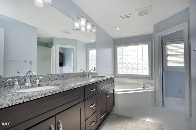 a bathroom with a granite countertop sink a large mirror and a bathtub with shower