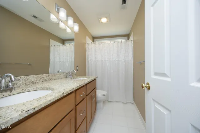 a bathroom with a granite countertop sink a toilet and a mirror