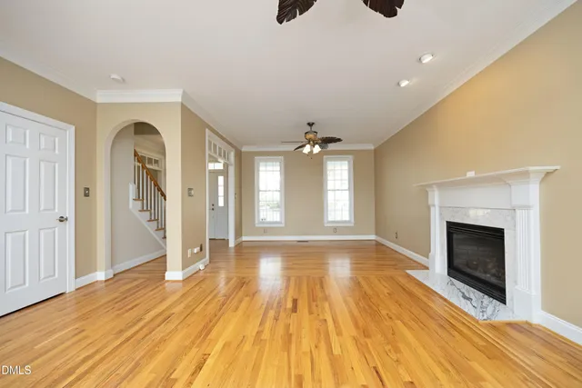 a view of an empty room with wooden floor fireplace and a window