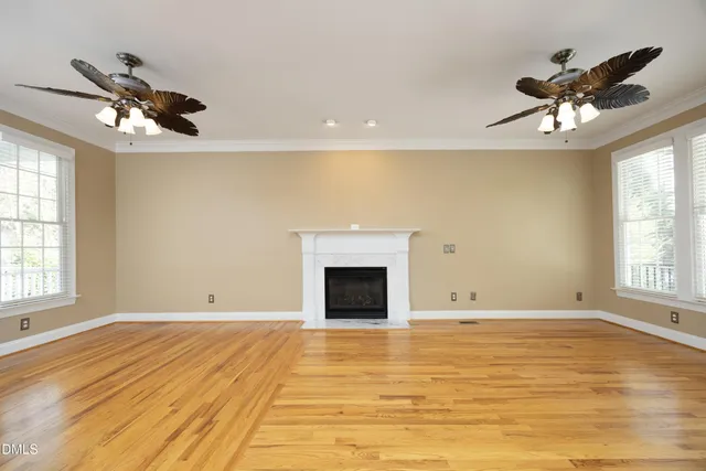 a view of an empty room with a window and chandelier fan