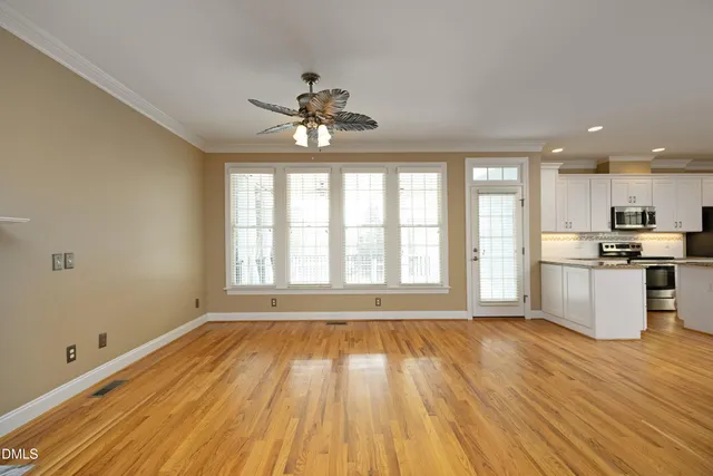 a view of an empty room with a window and wooden floor