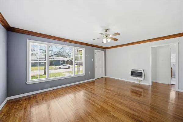 a view of an empty room with a window and wooden floor