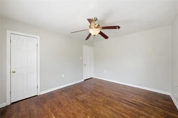 a view of a big room with wooden floor closet and ceiling fan