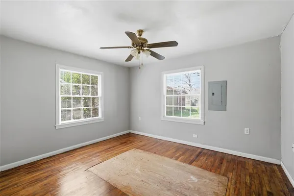 a view of empty room with wooden floor and fan