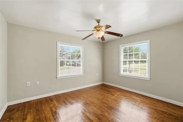 a view of an empty room with a window and wooden floor