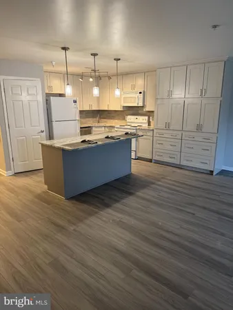 a large kitchen with kitchen island a stove a refrigerator and wooden floors