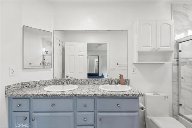 a bathroom with a granite countertop sink a mirror and a toilet