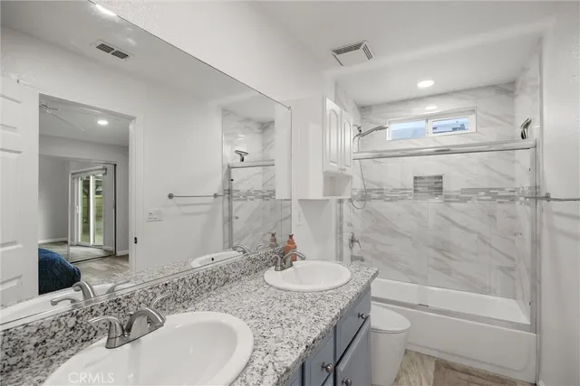 a bathroom with a granite countertop sink a toilet and shower