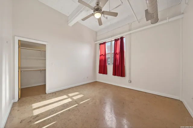an empty room with windows and ceiling fan