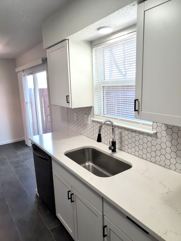 3413 Lynridge Drive, Unit B Austin, TX 78723 - Photo 11 of 23 Kitchen with light stone countertops, white cabinetry, a sink, decorative backsplash, and dishwasher