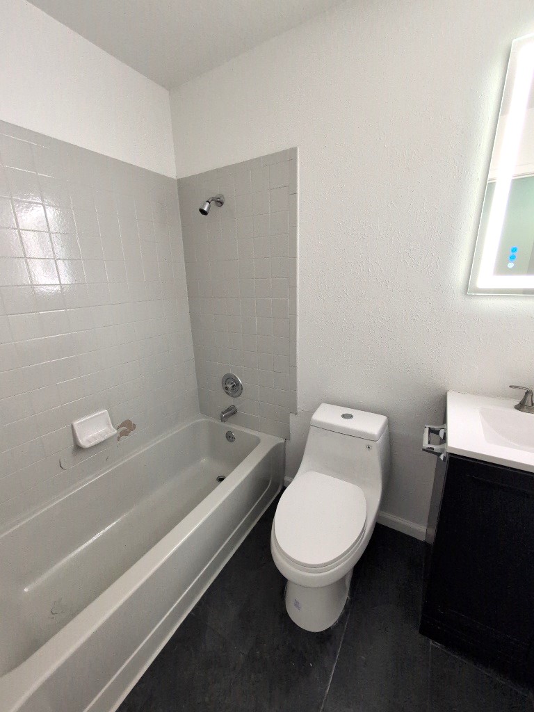 3413 Lynridge Drive, Unit B Austin, TX 78723 - Photo 17 of 23 Bathroom featuring tile patterned flooring, baseboards, washtub / shower combination, toilet, and vanity