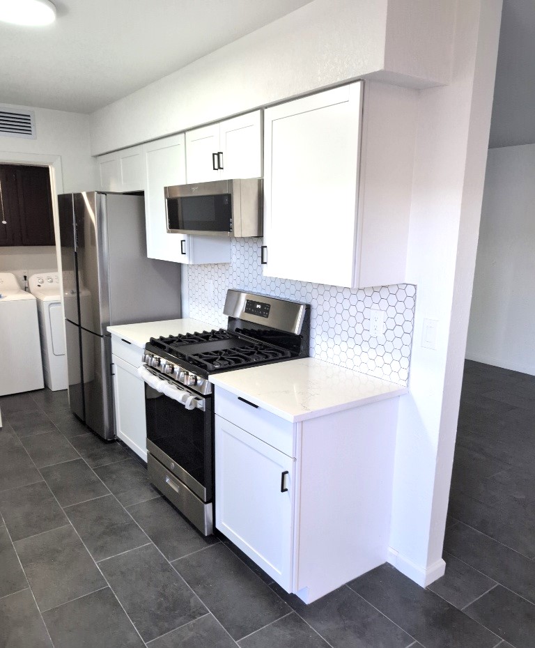 3413 Lynridge Drive, Unit B Austin, TX 78723 - Photo 10 of 23 Kitchen featuring washer and dryer, backsplash, white cabinetry, and appliances with stainless steel finishes