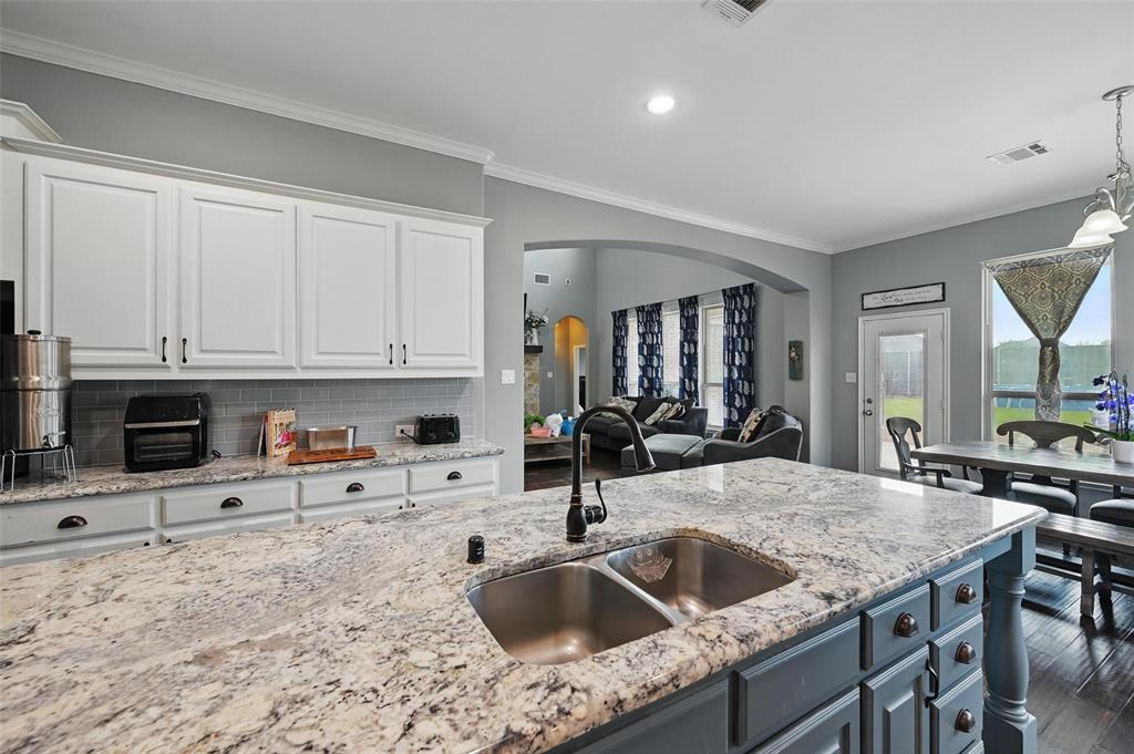 408 Mission Drive Forney, TX 75126 - Photo 13 of 40 Kitchen with a sink, arched walkways, white cabinets, ornamental molding, and tasteful backsplash