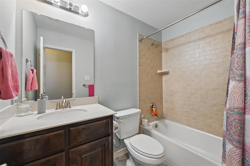408 Mission Drive Forney, TX 75126 - Photo 30 of 40 Bathroom featuring shower / bathtub combination with curtain, vanity, toilet, and a textured wall
