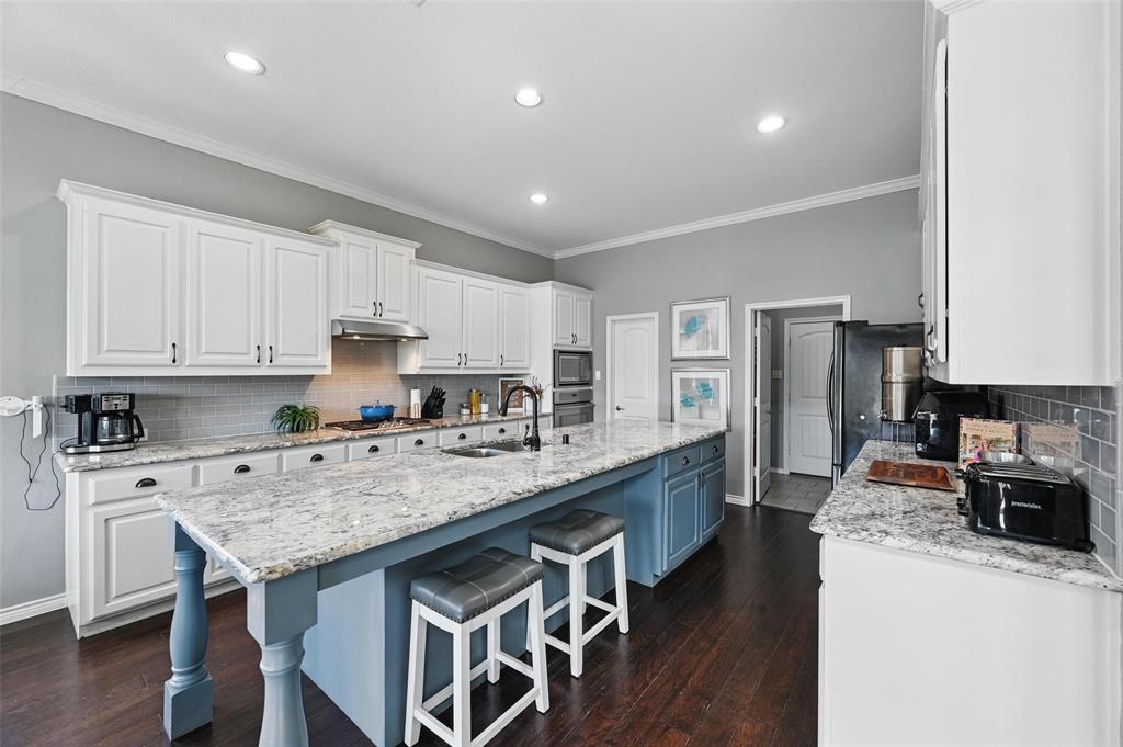 408 Mission Drive Forney, TX 75126 - Photo 8 of 40 Kitchen with a sink, stainless steel appliances, white cabinetry, under cabinet range hood, and ornamental molding