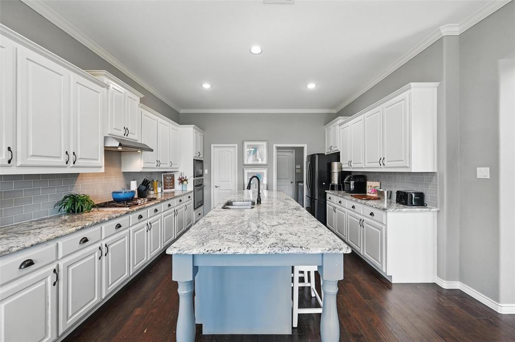 408 Mission Drive Forney, TX 75126 - Photo 9 of 40 Kitchen featuring under cabinet range hood, freestanding refrigerator, a sink, white cabinetry, and stainless steel gas stovetop