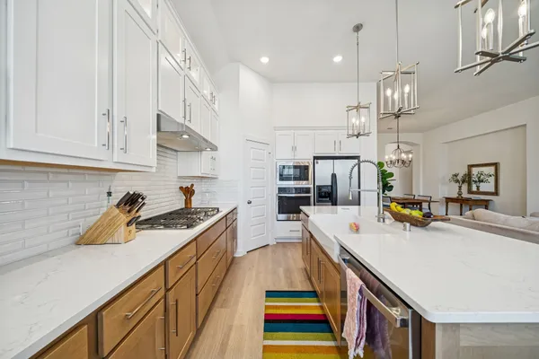 a kitchen with stainless steel appliances granite countertop a sink a stove and a wooden cabinets