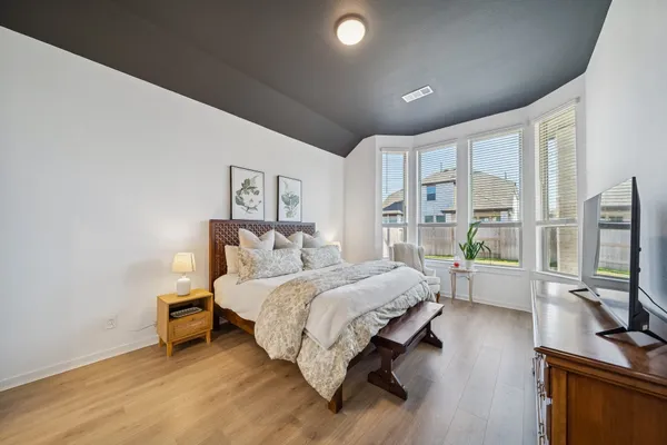 a bedroom with a bed tv and a large window