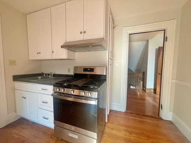 a kitchen with granite countertop white cabinets and stainless steel appliances
