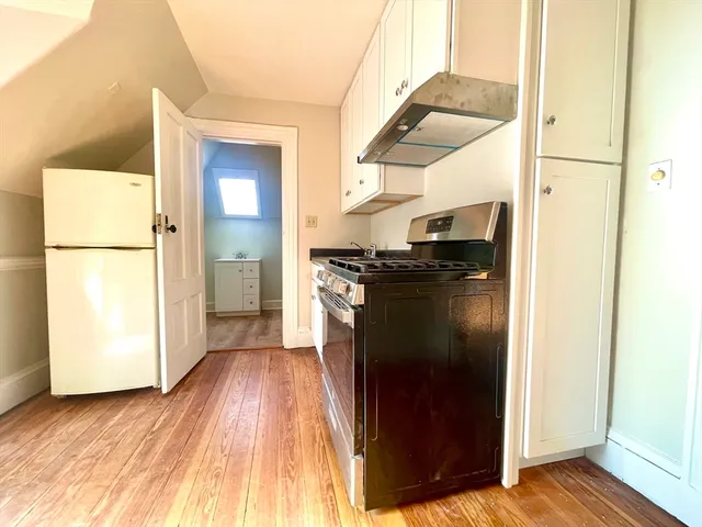 a kitchen with a refrigerator a sink and wooden floor