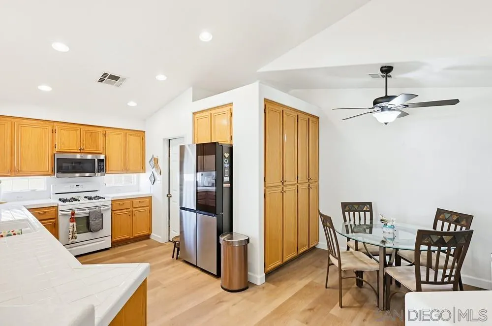 2501 Columbine Road Alpine, CA 91901 - Photo 12 of 44 a kitchen with stainless steel appliances kitchen island granite countertop a table chairs and a refrigerator