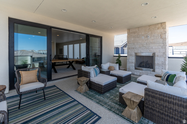 Covered outdoor patio with a built-in stone fireplace, recessed lighting, and large sliding glass doors