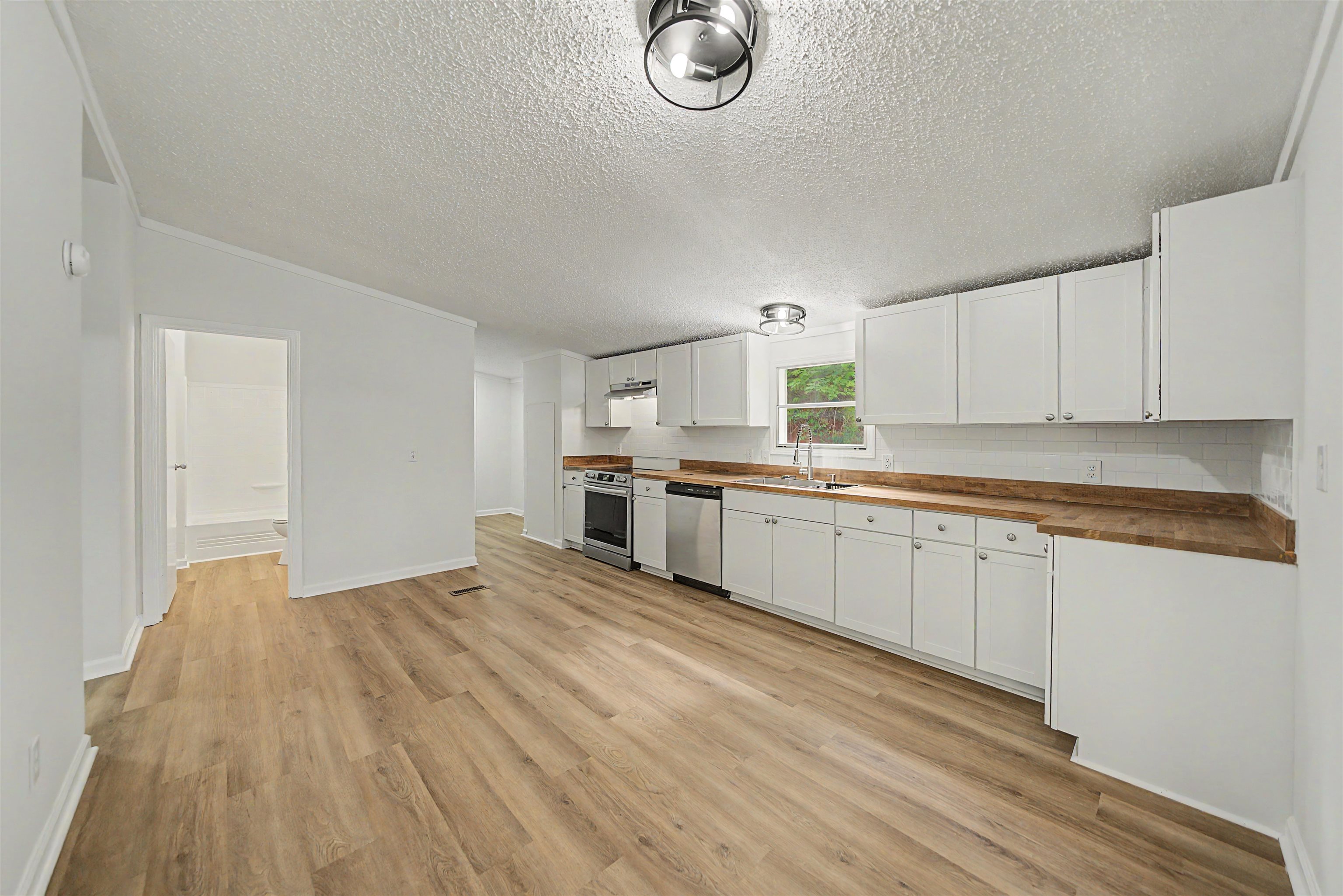 890 Burks Road Savannah, TN 38372 - Photo 8 of 40 a kitchen with granite countertop a stove a sink dishwasher and white cabinets with wooden floor