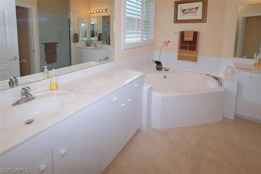 4664 Fairloop Run Lehigh Acres, FL 33973 - Photo 15 of 24 a spacious bathroom with a bathtub sink and mirror