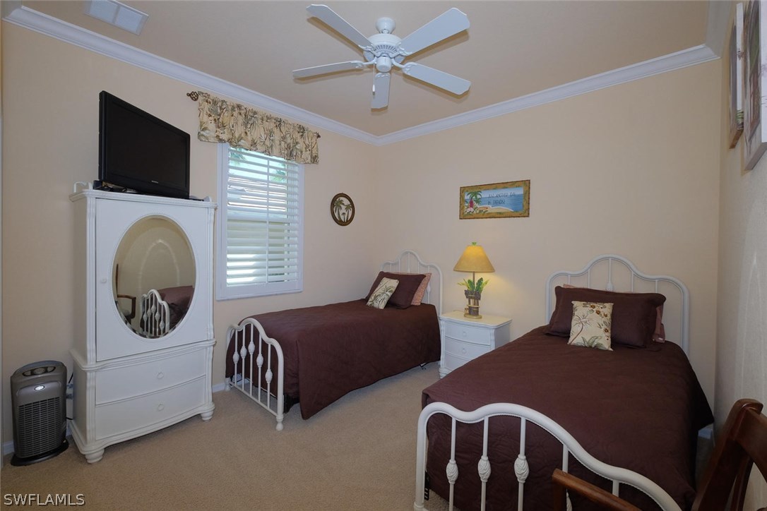 4664 Fairloop Run Lehigh Acres, FL 33973 - Photo 16 of 24 a bedroom with two beds and a chandelier