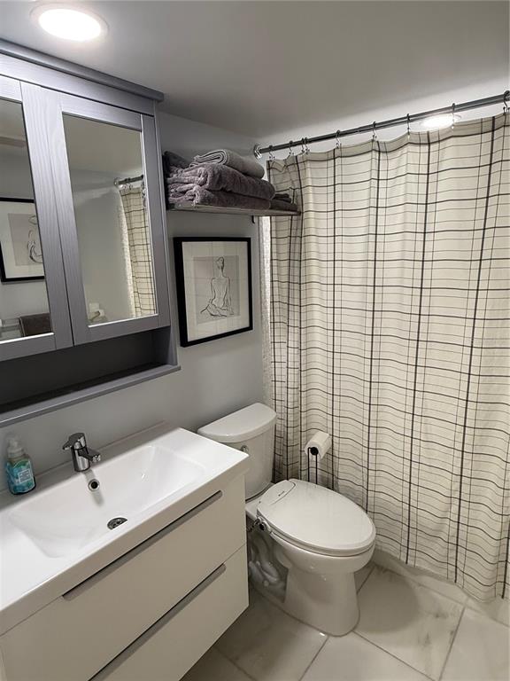 1868 Shore Drive South, Unit 608 South Pasadena, FL 33707 - Photo 18 of 36 a bathroom with a toilet a sink a mirror and shower curtain