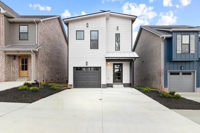a front view of a house with garage and plants